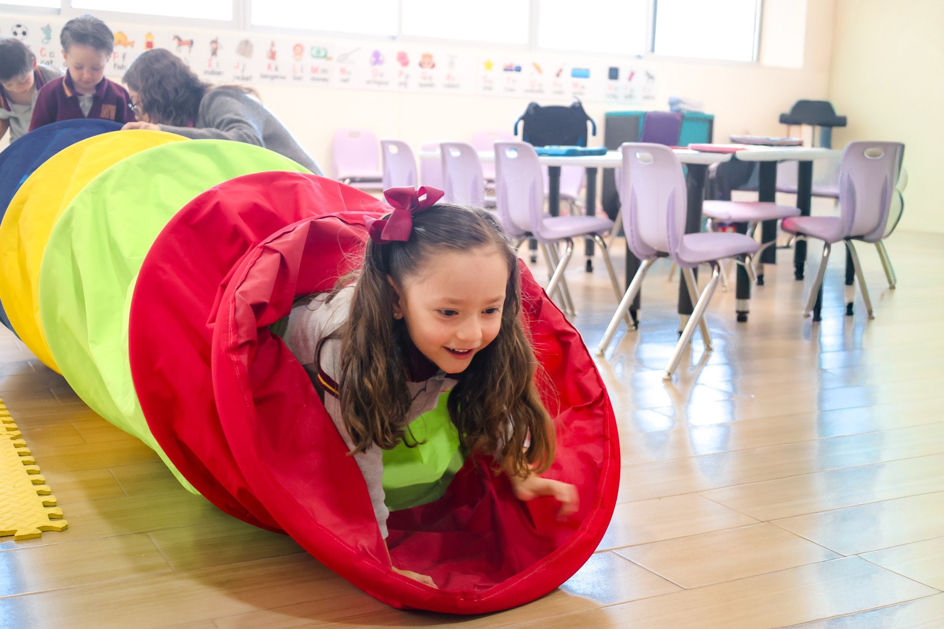 Kinder children playing in tunnel during outdoor recess at Newland