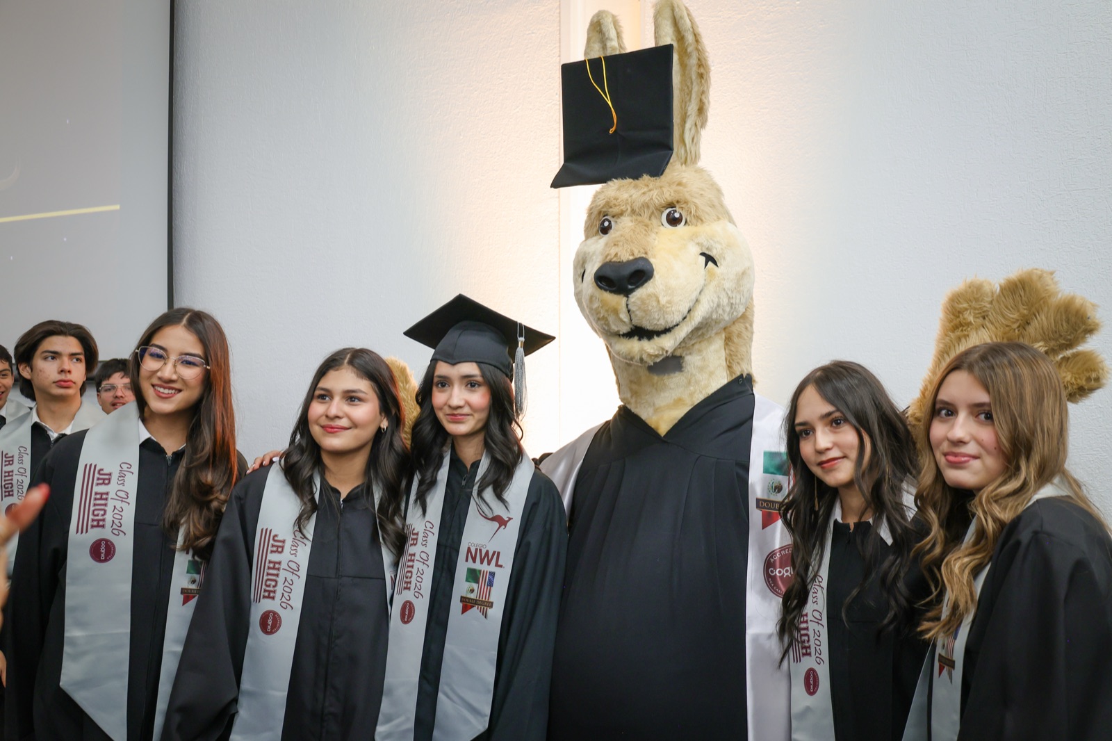 NWL graduates celebrating with the kangaroo mascot in cap and gown
